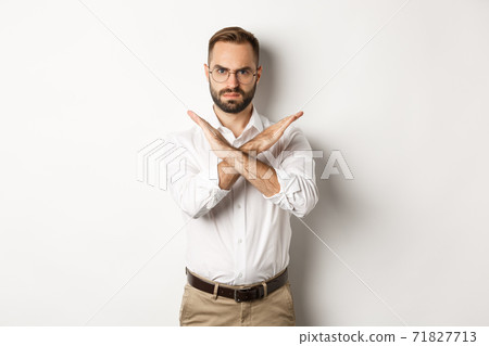 Angry businessman frowning and showing cross, stop you, telling no and prohibit something, standing over white background Angry businessman frowning and showing cross, stop you, telling no and prohibit something, standing over white background 71827713