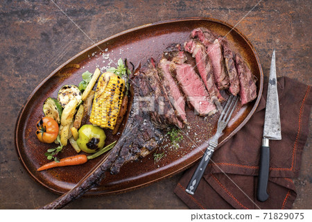 Traditional barbecue dry aged sliced wagyu tomahawk beef steak with grilled vegetable 71829075