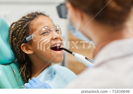 Dentist curing patient's teeth 71830696