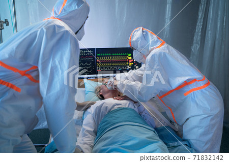 Doctors and covid-19 patient with oxygen mask in bed in hospital, coronavirus concept. 71832142
