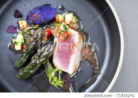 Traditional fried tuna fish filet with green asparagus, blue potatoes und vegetable chili relish 71833242
