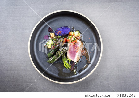Traditional fried tuna fish filet with green asparagus, blue potatoes und vegetable chili relish Traditional fried tuna fish filet with green asparagus, blue potatoes und vegetable chili relish 71833245