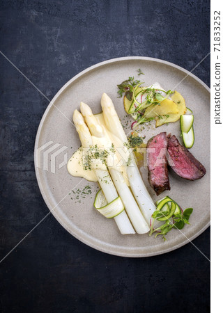 dry aged sliced fillet steak with white asparagus in hollandaise sauce and roast potatoes dry aged sliced fillet steak with white asparagus in hollandaise sauce and roast potatoes 71833252