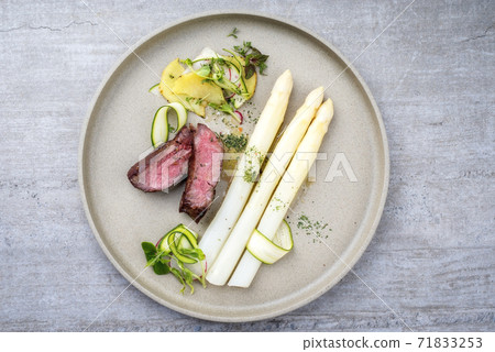 dry aged sliced fillet steak with white asparagus in hollandaise sauce and roast potatoes  71833253