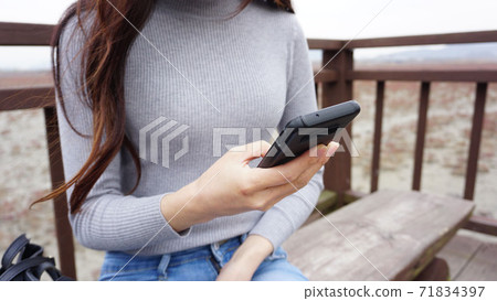播放用一隻手的長發婦女手機 播放用一隻手的長發婦女手機 71834397