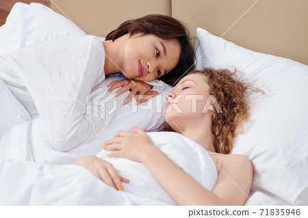 Woman looking at sleeping girlfriend Woman looking at sleeping girlfriend 71835946