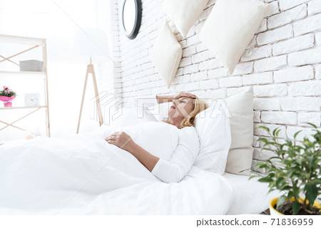 A woman has a headache lying in bed. A woman has a headache lying in bed. 71836959