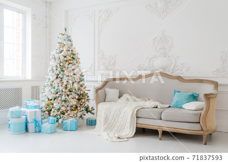 Stylish Christmas interior with an elegant sofa. Comfort home. Presents gifts underneath the tree in living room Stylish Christmas interior with an elegant sofa. Comfort home. Presents gifts underneath the tree in living room 71837593