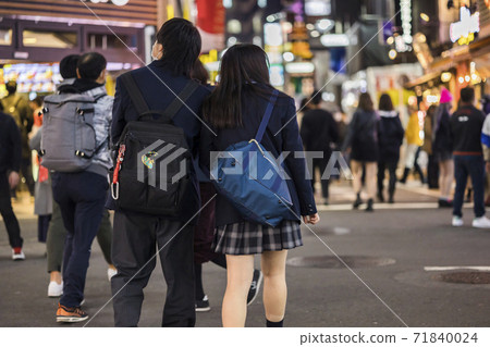 Back view of a high school couple in uniform walking in Shibuya Center Gai 71840024