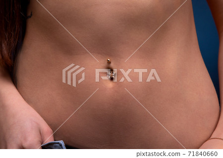 Close-up image of woman's slim belly with piercing 71840660
