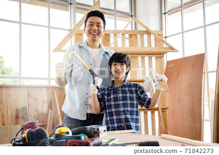 ็Happy Asian father and son doing woodwork together in carpentry workshop. ็Happy Asian father and son doing woodwork together in carpentry workshop. 71842273