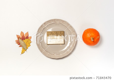 empty name card on a gray vintage plate, on a white background with a small orange pumpkin and dry autumn leaves empty name card on a gray vintage plate, on a white background with a small orange pumpkin and dry autumn leaves 71843470