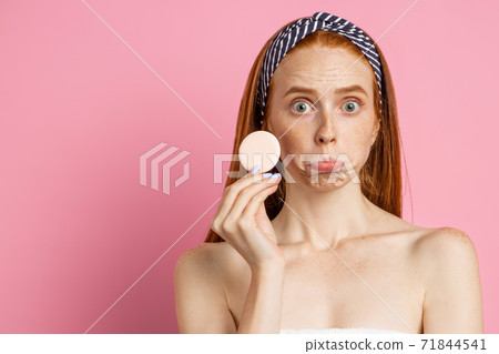 Beautiful woman with facial mask on pink background Beautiful woman with facial mask on pink background 71844541