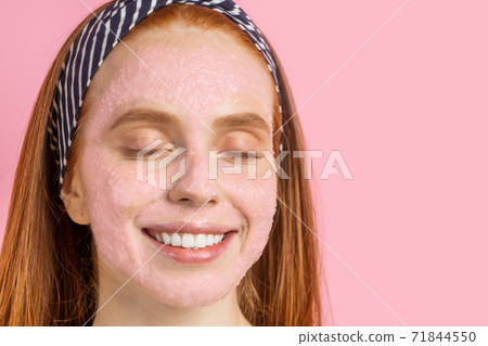 Beautiful woman with facial mask on pink background Beautiful woman with facial mask on pink background 71844550