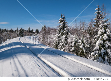 Railway through snowy fir forest and remote alpine helmet in Carpathian mountains, snow drifts on wayside Railway through snowy fir forest and remote alpine helmet in Carpathian mountains, snow drifts on wayside 71844727