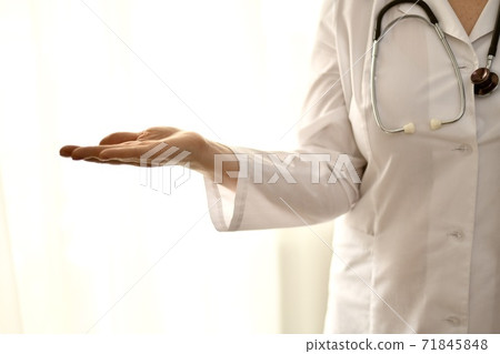 The doctor in a white robe stands, closeup, the left side of the person on the right, with empty palm showing anything. The doctor in a white robe stands, closeup, the left side of the person on the right, with empty palm showing anything. 71845848