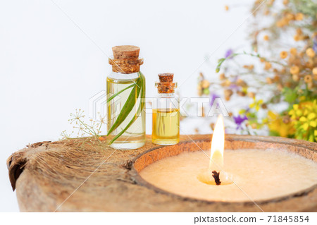 Two essential herbal oil bottles and burning organic candle closeup Two essential herbal oil bottles and burning organic candle closeup 71845854