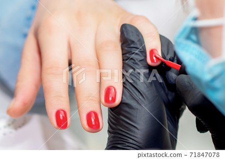 Manicurist paints nails. 71847078