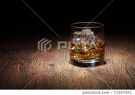 Scotch in glass tumbler with ice rocks on old wood surface Scotch in glass tumbler with ice rocks on old wood surface 71847841