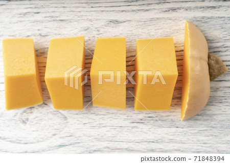 Sliced pumpkin slices on a white and black wooden table. Several pieces stacked in a row. Sliced pumpkin slices on a white and black wooden table. Several pieces stacked in a row. 71848394