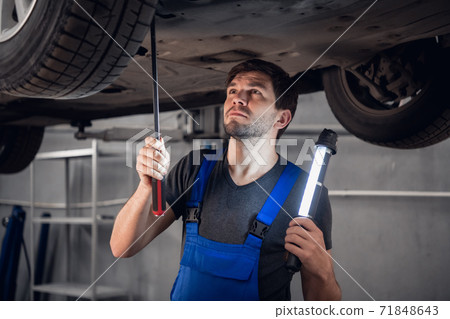 Worker checks the car bottom and shines a flashlight Worker checks the car bottom and shines a flashlight 71848643