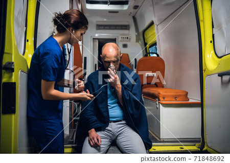 A young female paramedic on duty, taking care of an injured man 71848692