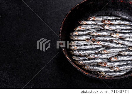 Raw trout lie on a black stone chopping board on a dark concrete table Raw trout lie on a black stone chopping board on a dark concrete table 71848774
