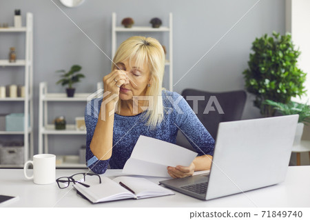 Tired senior woman receiving bankruptcy notification or rejection letter and crying Tired senior woman receiving bankruptcy notification or rejection letter and crying 71849740