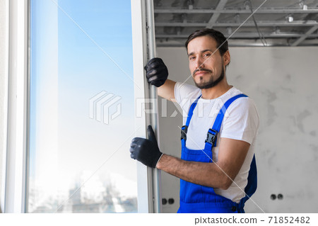 Repairman in gloves installs the window in the room Repairman in gloves installs the window in the room 71852482