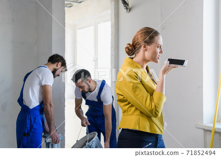 Flat owner talking on the phone at a construction site Flat owner talking on the phone at a construction site 71852494