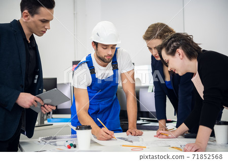 Construction team working with compasses and blueprints on an ar Construction team working with compasses and blueprints on an ar 71852568