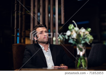 a tired man sits at a table in a restaurant after work a tired man sits at a table in a restaurant after work 71852853