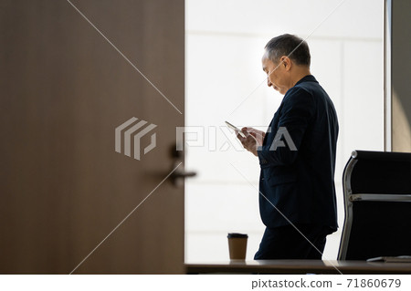 A man in the back looking at an email A man in the back looking at an email 71860679