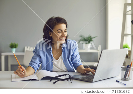 Smiling female teacher conducts online lesson via video chat on laptop while staying at home. 71861682