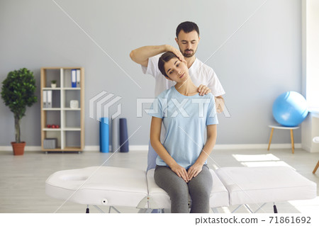 Professional chiropractor doing neck massage to young woman in modern medical office 71861692