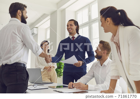 Friendly business team manager shaking hands with happy employee during work meeting 71861770