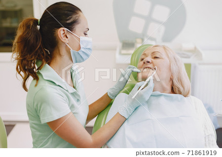 Dentist looking her old patient with tools Dentist looking her old patient with tools 71861919