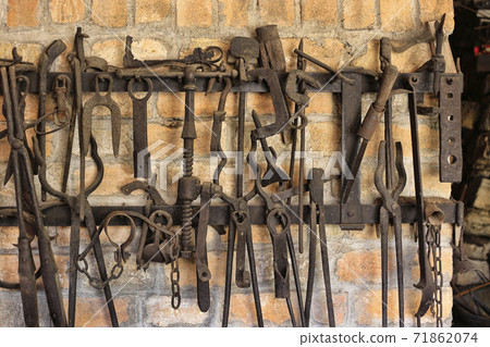Close-up of work tools hanging at blacksmith shop Close-up of work tools hanging at blacksmith shop 71862074