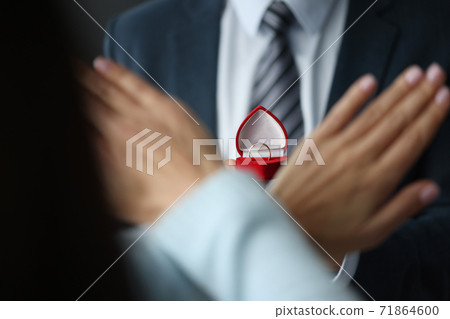 Man is holding wedding ring. Woman is making negative gesture. 71864600