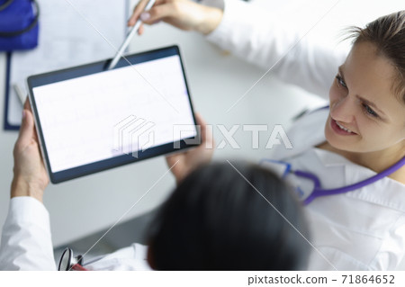 Two doctors at workplace are looking at tablet. Two doctors at workplace are looking at tablet. 71864652