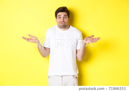 Clueless man shrugging, spread hands sideways confused, dont know anything, standing over yellow background Clueless man shrugging, spread hands sideways confused, dont know anything, standing over yellow background 71866331