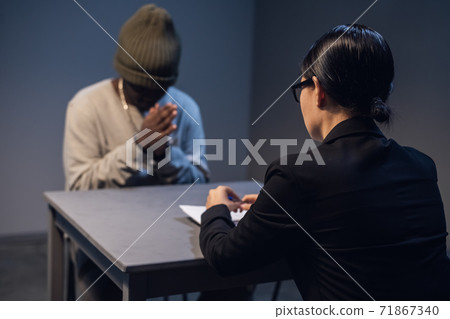 At the police station, a girl investigator interrogates a black guy who is sitting in front of her in handcuffs 71867340