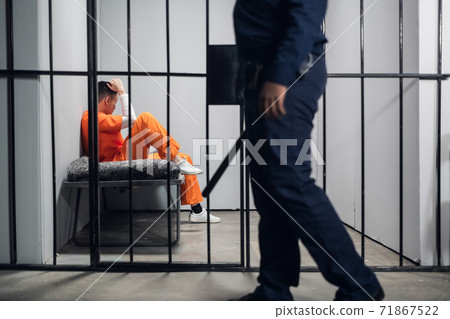 A male warden guards cells with dangerous criminals in a high-security prison. Dangerous profession. A male warden guards cells with dangerous criminals in a high-security prison. Dangerous profession. 71867522