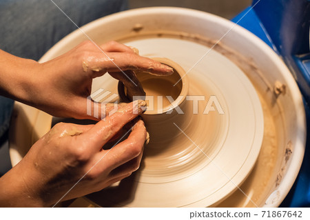 on a potter's wheel, a young potter makes a preparation for a pot out of clay. 71867642