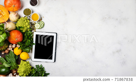 Tablet computer with blank screen Different vegetables and greens. Top view with place for text. Banner 71867838