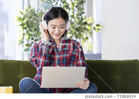 A young woman wearing headphones and looking at a computer screen 71868024
