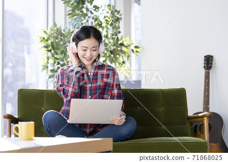 A young woman wearing headphones and looking at a laptop screen A young woman wearing headphones and looking at a laptop screen 71868025
