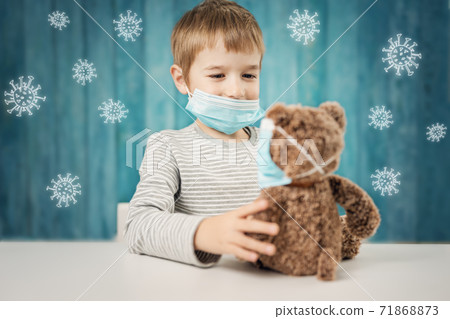 Little boy sitting at the table with a teddy bear in medical facial masks 71868873