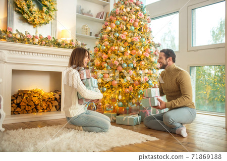 Young happy couple sitting near christmas tree Young happy couple sitting near christmas tree 71869188
