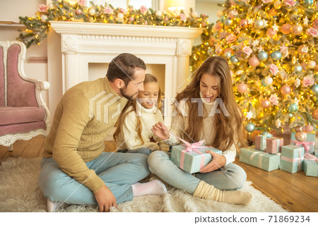 Young family feeeling happy opening christmas gifts Young family feeeling happy opening christmas gifts 71869234